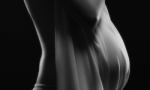 Fotografia de mulher grávida com um lençol sobre a barriga dela
